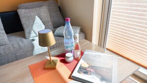 A room with a sofa, a table with a lamp, a bottle, a jar, and a book. - Apartment 'Fewotraum Müritz Möwe 3' with Private Terrace and Wi-Fi (Röbel)