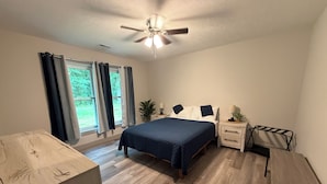 A bedroom with a bed, bedside tables, a nightstand, a ceiling fan, and a window with curtains. -  "Last Light", This Perfect 3-bedroom, 2 bath cottage in quaint GOTL. (Geneva)
