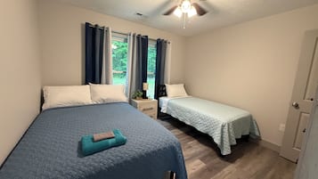 Une chambre avec deux lits, un ventilateur de plafond et une fenêtre avec des rideaux.
