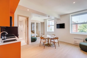 A modern kitchen with a built-in oven, a dining area with a round table and chairs, and a large window providing natural light. - 311 Cook - Apartment in Old Quebec (Québec)