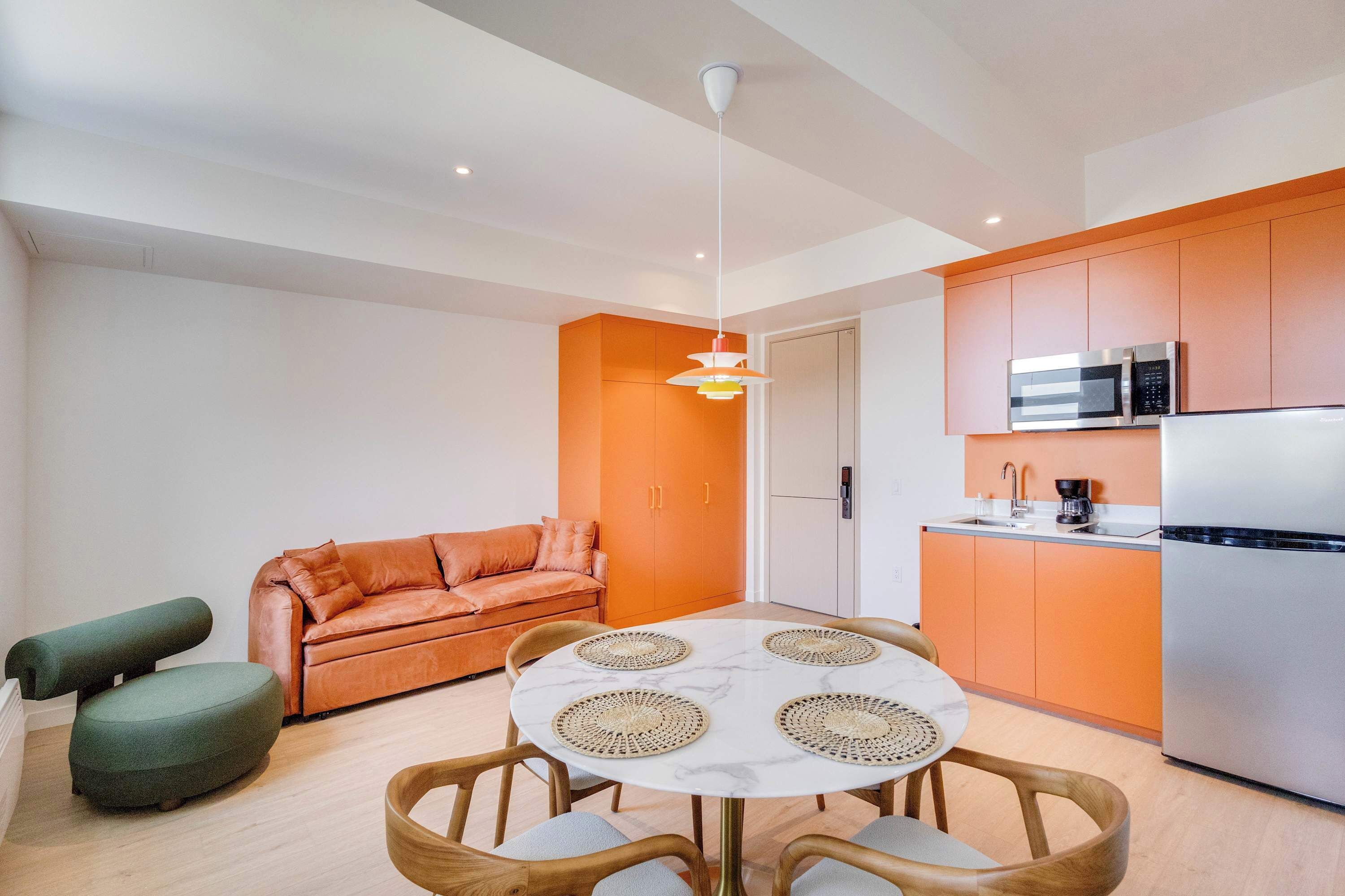 A compact living space with a kitchenette, a dining area with a round table, and a sofa.