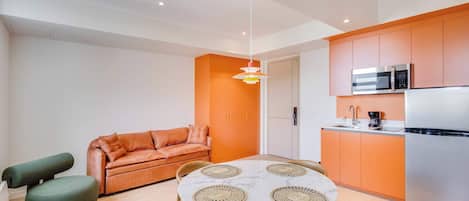 A compact living space with a kitchenette, a dining area with a round table, and a sofa.