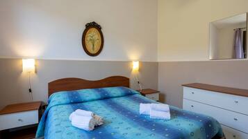 Una camera da letto con un letto, comodini, un mobiletto, uno specchio e lampade a parete.