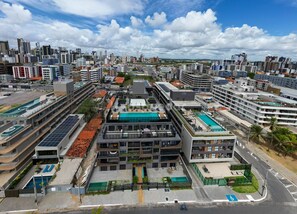 Un edificio moderno con varios pisos, paneles solares en la azotea y una piscina.