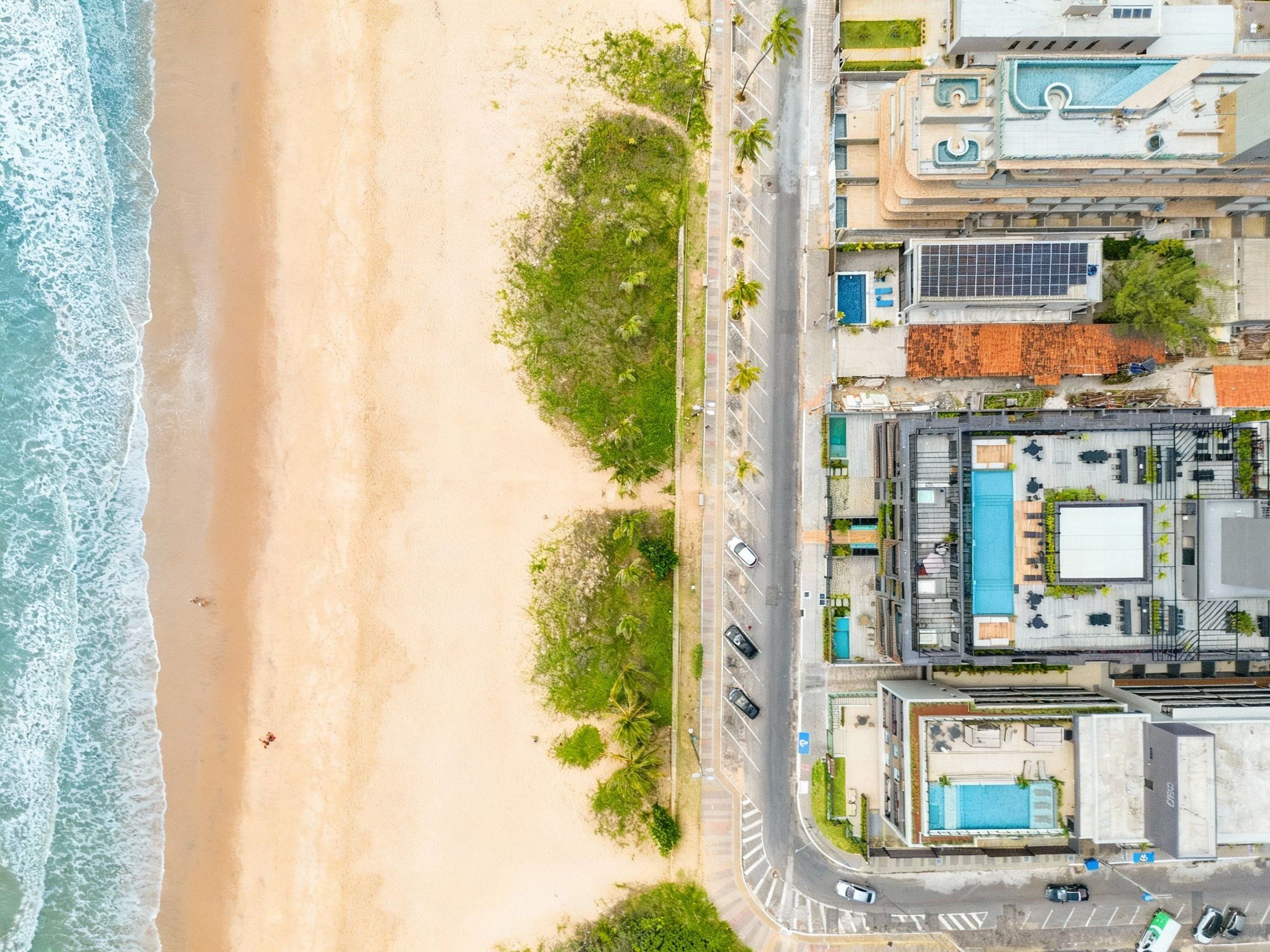 Vista aérea de um hotel à beira-mar, com piscina e estacionamento.