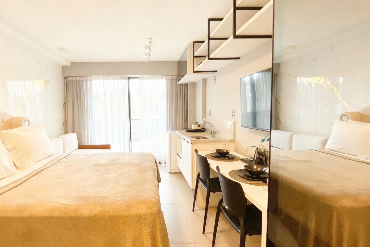 Habitación de hotel con dos camas, un escritorio y un espejo grande.