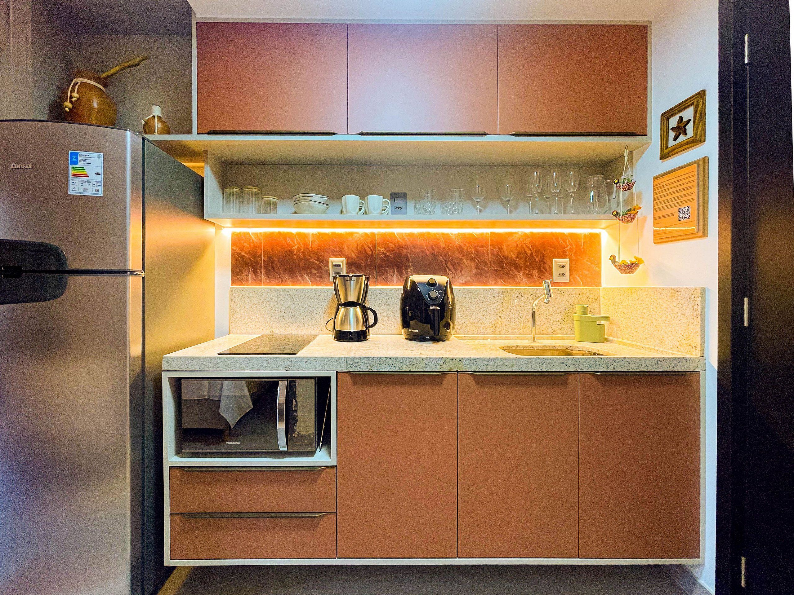 Uma cozinha compacta com forno embutido, cafeteira e torradeira.
