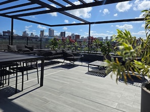 An outdoor patio with seating and plants, overlooking a cityscape. - Beach Haus By Hosppedar (João Pessoa)