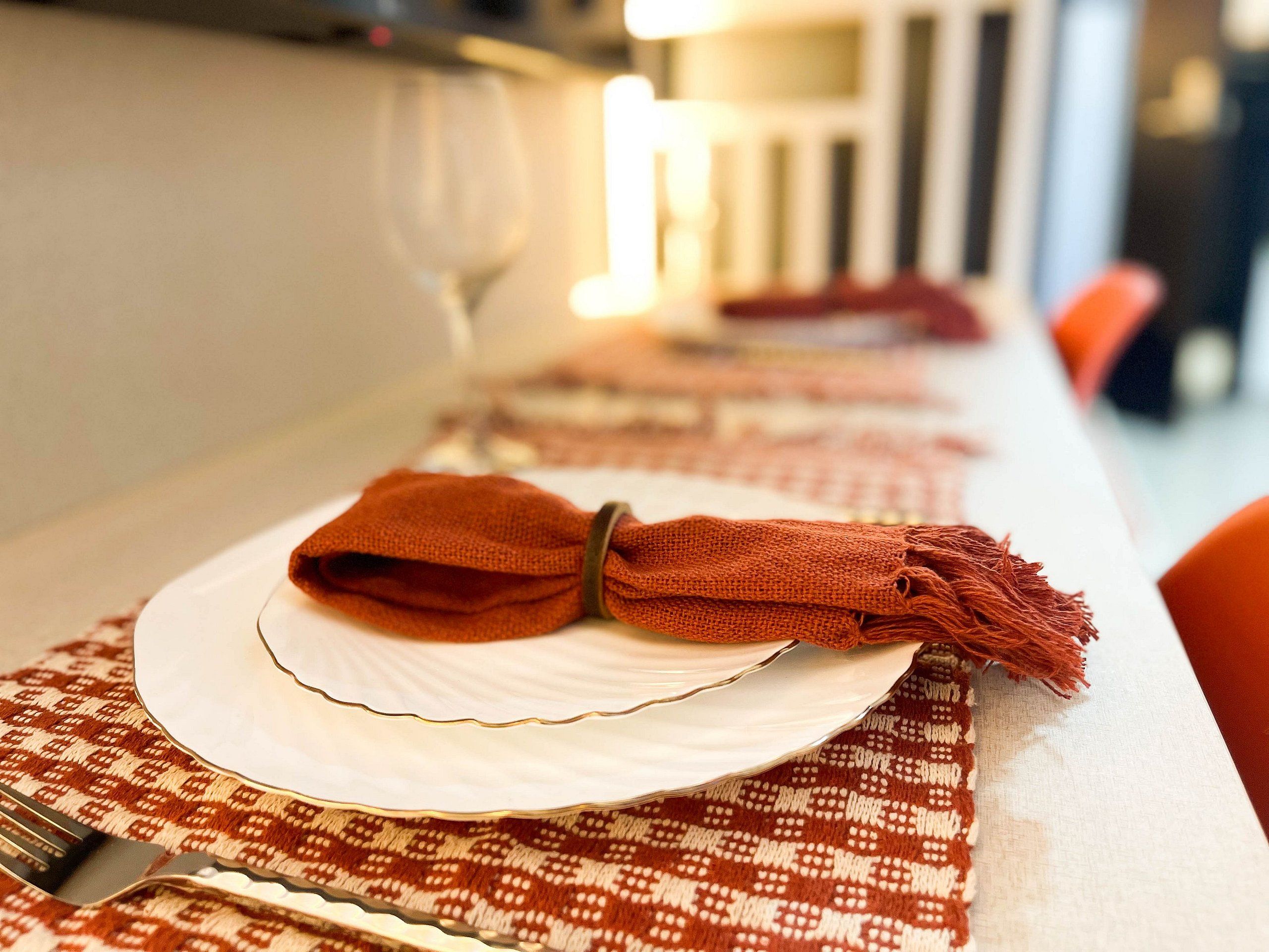 Une table dressée avec des assiettes blanches, une serviette pliée et une fourchette.