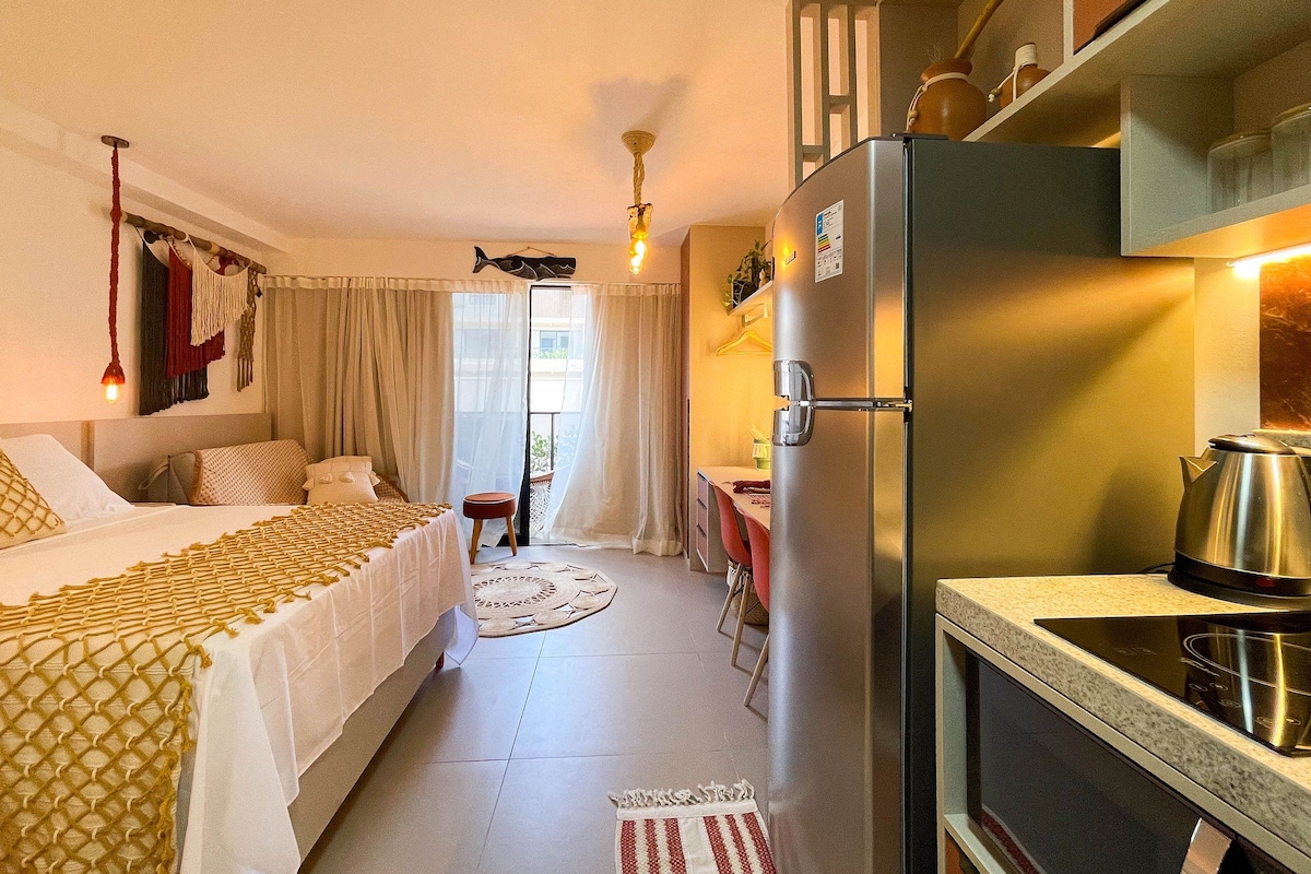 Habitación de hotel compacta con cama, kitchenette, zona de comedor y baño.