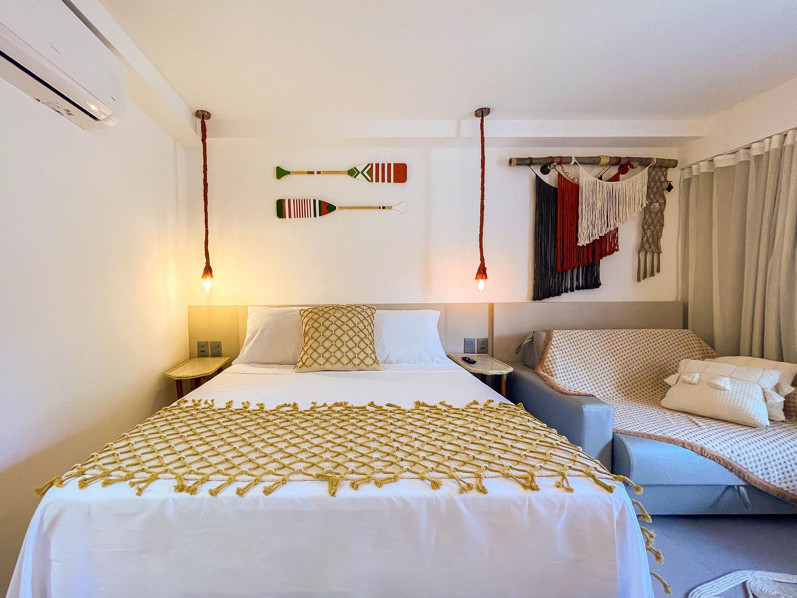 Een hotelkamer met een bed, een bank en een wandrek met kleding.