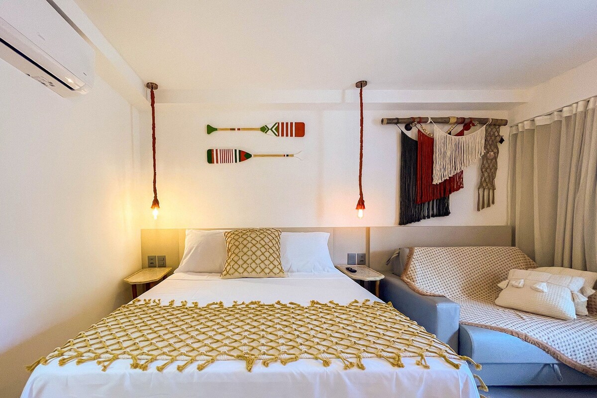 Une chambre d’hôtel avec un lit, un canapé et un porte-vêtements fix é au mur.