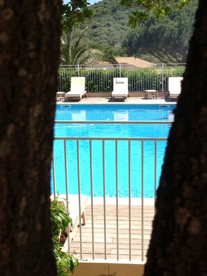 A swimming pool with a metal railing, surrounded by lounge chairs and a wooden deck. - Villa with a pool near Palombaggia Beach (Porto-Vecchio)