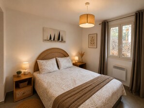 Um quarto com cama, abajures, uma janela com cortinas e obras de arte na parede.