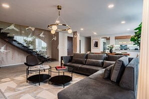 A modern living room with a sofa, coffee table, and a staircase with a glass railing. - Group Friendly | Private Terrace & BBQ in Roma Sur (Mexico City)