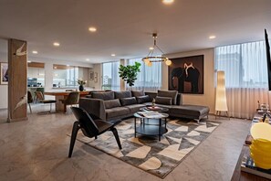A modern living room with a sectional sofa, a coffee table, and a dining area in the background. - Group Friendly | Private Terrace & BBQ in Roma Sur (Mexico City)