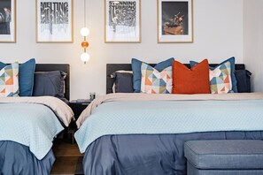 A hotel room with two beds, each with a headboard, a bedside table, and a lamp. There are framed pictures on the wall. - Group Friendly | Private Terrace & BBQ in Roma Sur (Mexico City)