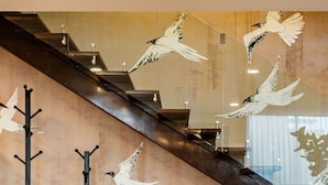 A modern interior with a staircase, a glass table with books, and wall-mounted coat hooks. - Roma Sur Stay: Private Elevator, BBQ & Rooftop (Mexico City)