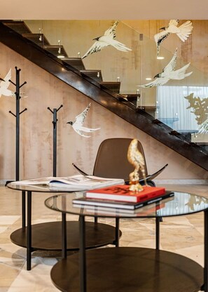 Ein modernes Interieur mit einer Treppe, einem Glastisch mit Büchern und Wandhaken für Kleidung.