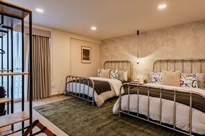 Ein Hotelzimmer mit zwei Betten, einem großen Fenster mit Vorhängen, einem Holzstuhl und einem kleinen Tisch.