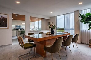 A modern dining area with a glass-top table, six chairs, and a view of the city through large windows. - Roma Sur Stay: Private Elevator, BBQ & Rooftop (Mexico City)