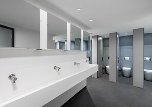 A modern restroom with a long white sink, multiple mirrors, and a grey floor.
