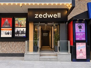 The exterior of the Zedwell building with a modern design, featuring a glass entrance and a sign above the door.