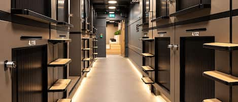 A hotel corridor with lockers numbered 4.116 and 4.132, and a reception area in the distance.