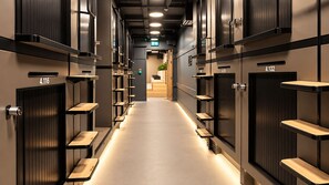 A hotel corridor with lockers numbered 4.116 and 4.132, and a reception area in the distance.