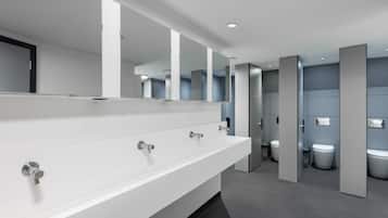 A modern restroom with a long white sink, multiple mirrors, and a grey floor.