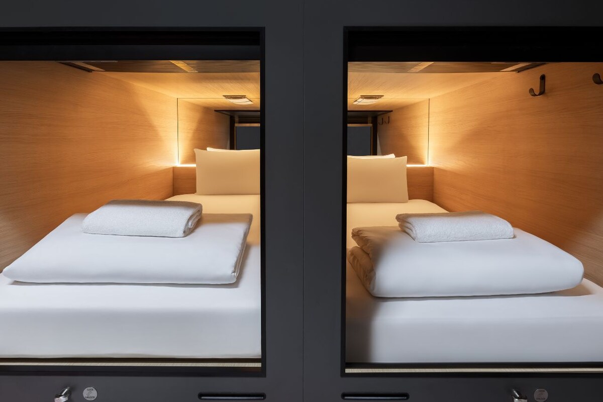 A mirrored room with two beds, each with a pillow and a blanket.