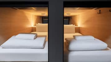 A mirrored room with two beds, each with a pillow and a blanket.