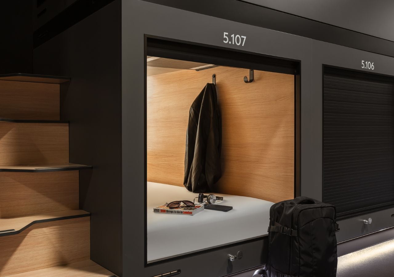 Een hotelkamer met een grote spiegel, een koffer en een boek getiteld '1000 dingen om in Londen te doen' op het aanrecht.