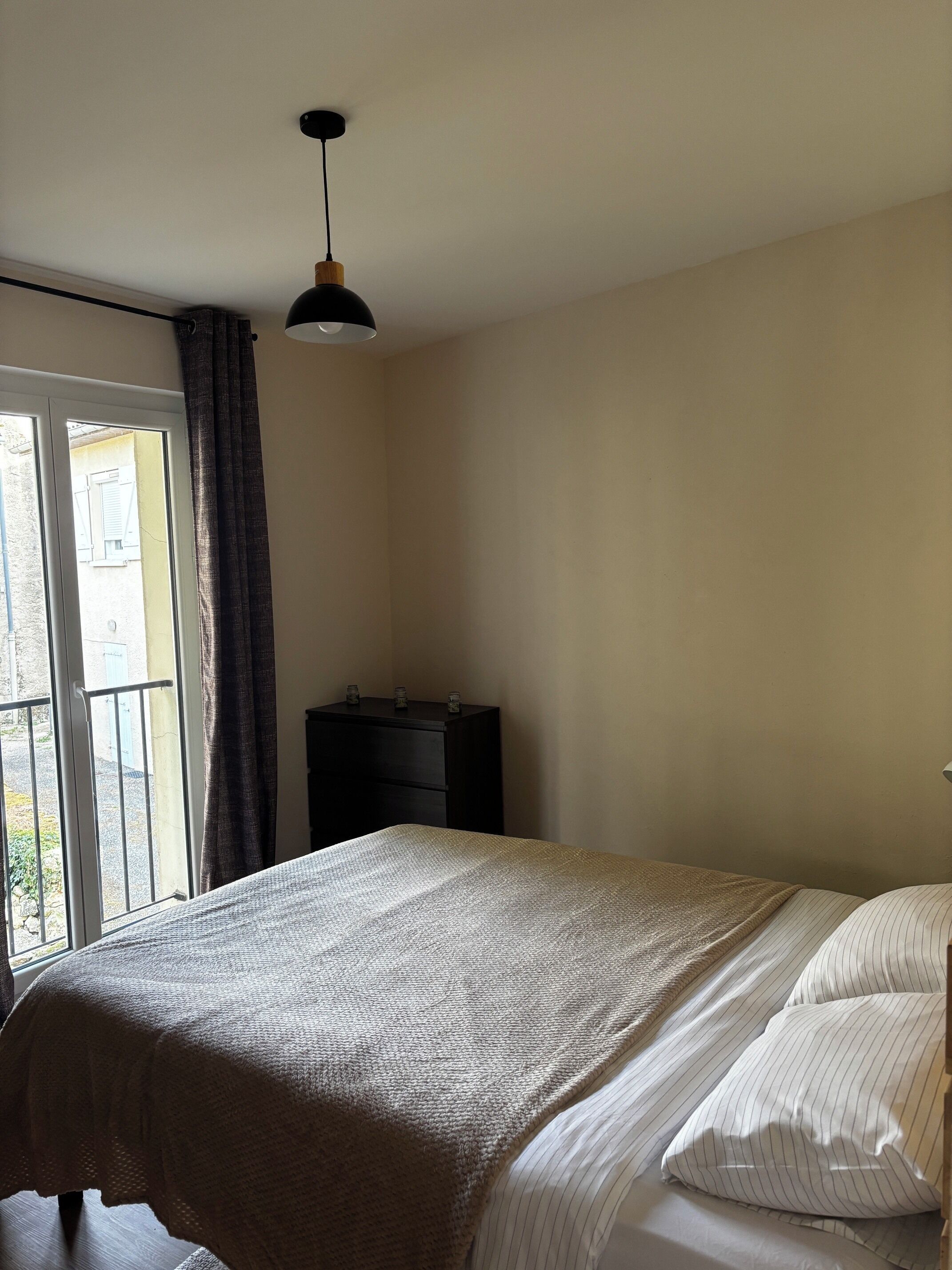 A bedroom with a bed, a dresser, and a window with curtains.