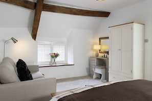 Ein Schlafzimmer mit einem Bett, einem Schreibtisch, einem Stuhl, einem Kleiderschrank, einem Fenster mit Rollläden und einer Lampe.