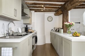 A kitchen with a wooden ceiling, a clock, and a vase with flowers. - The Mews Hideaway -  a cottage that sleeps 4 guests  in 2 bedrooms (Fairford)