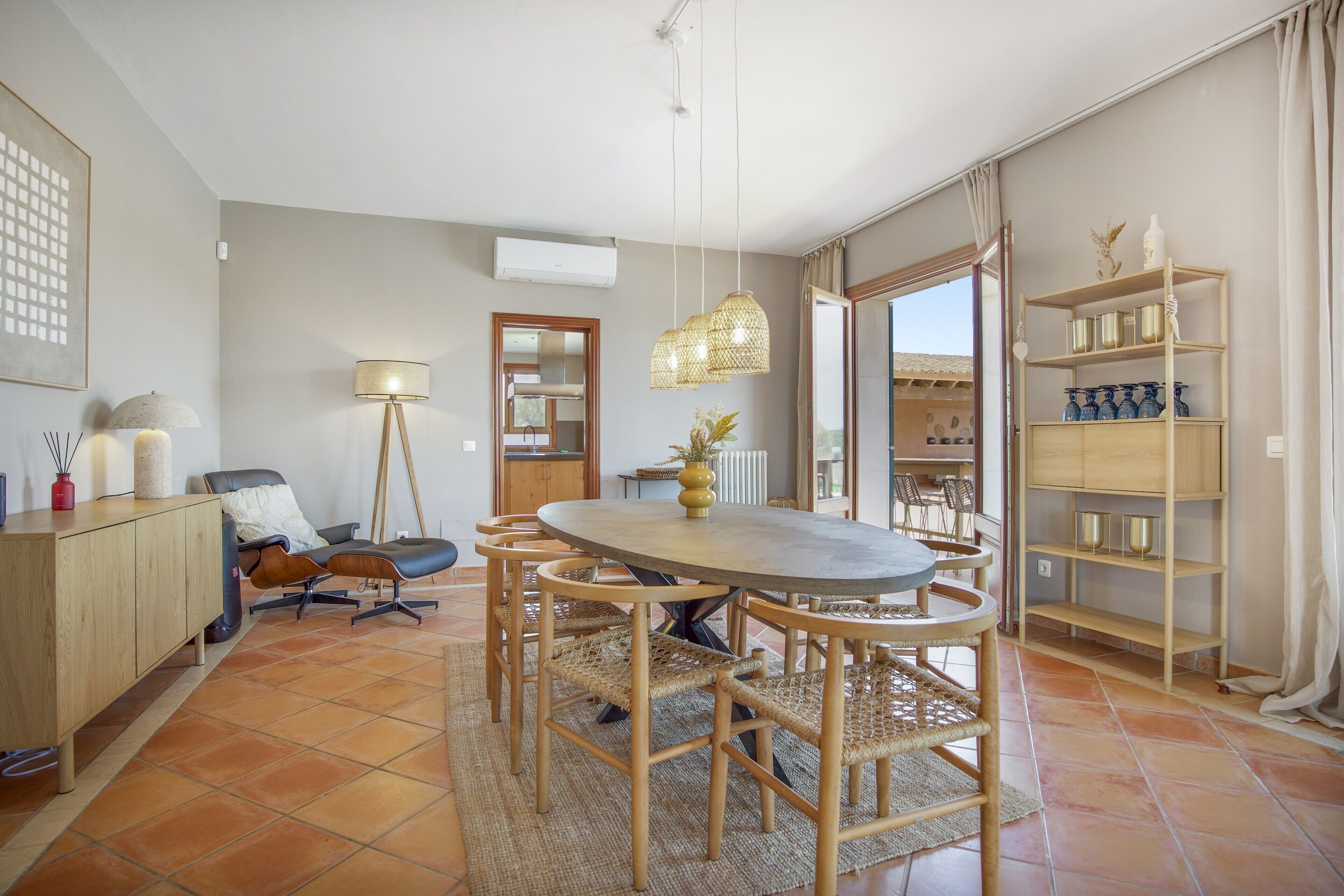 A dining area with a round table, chairs, a floor lamp, and a bookshelf.