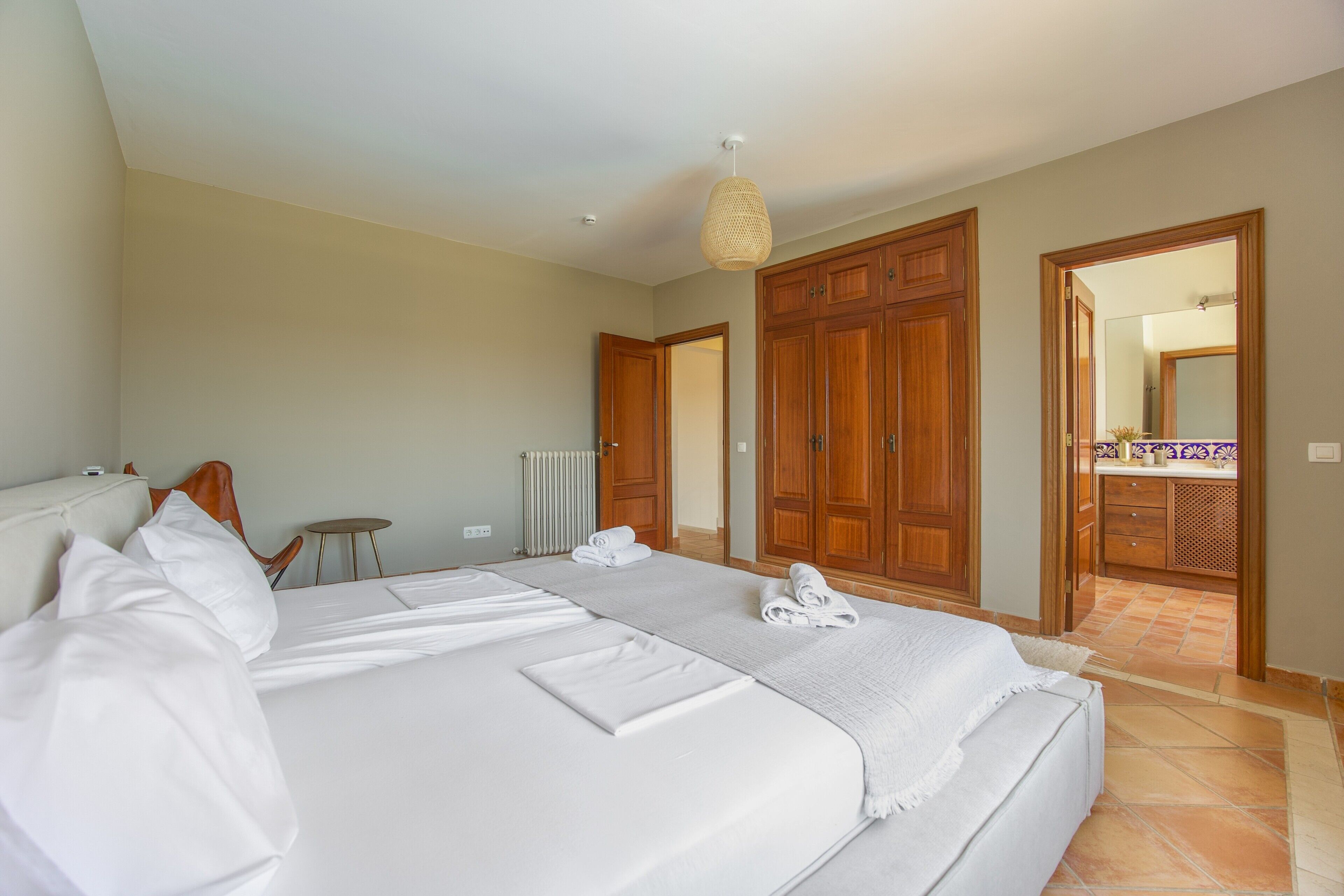 A hotel room with a large bed, wooden wardrobe, and a bathroom visible through an open door.