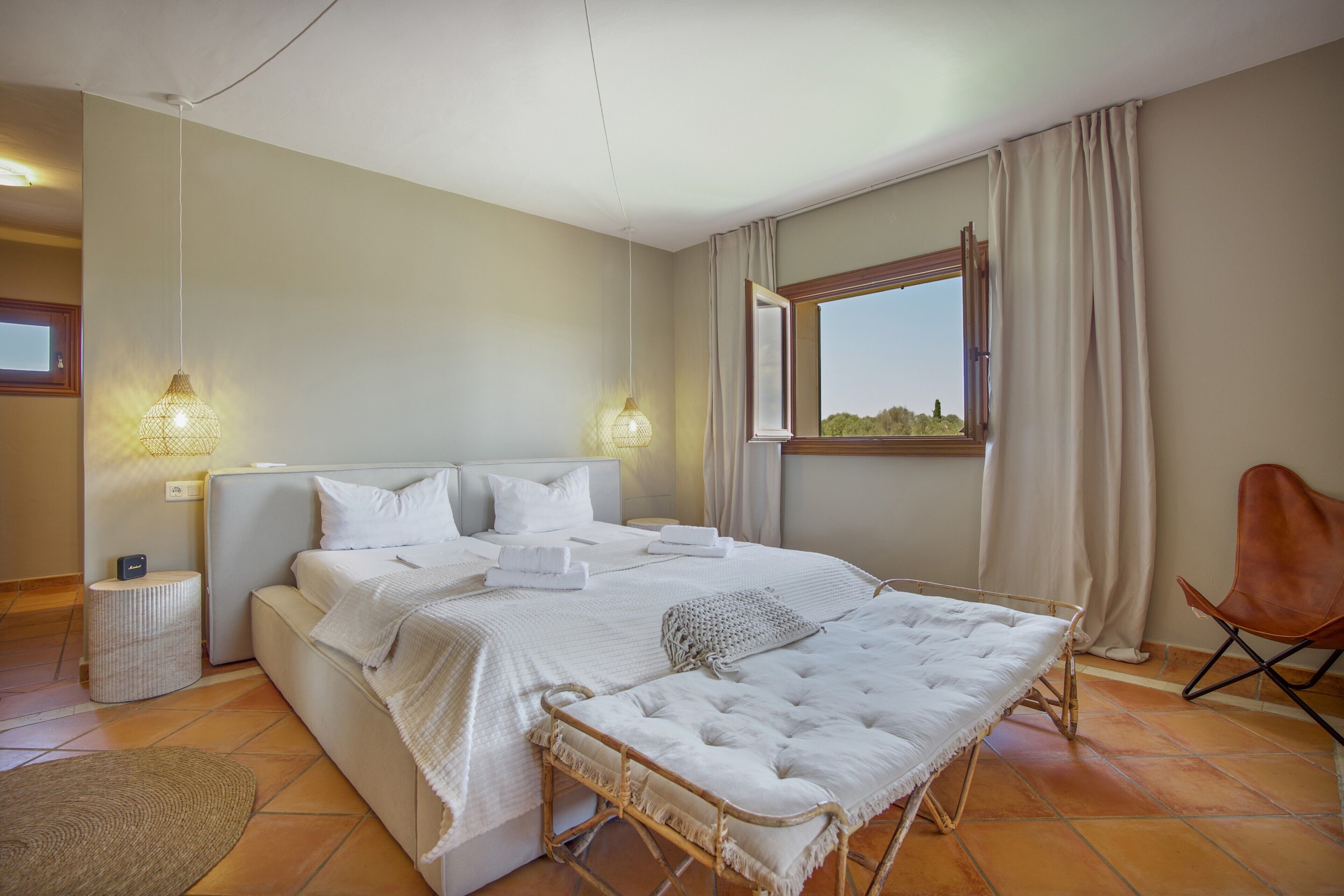 Une chambre à coucher avec un lit, des lampes de chevet, une fenêtre et une chaise.