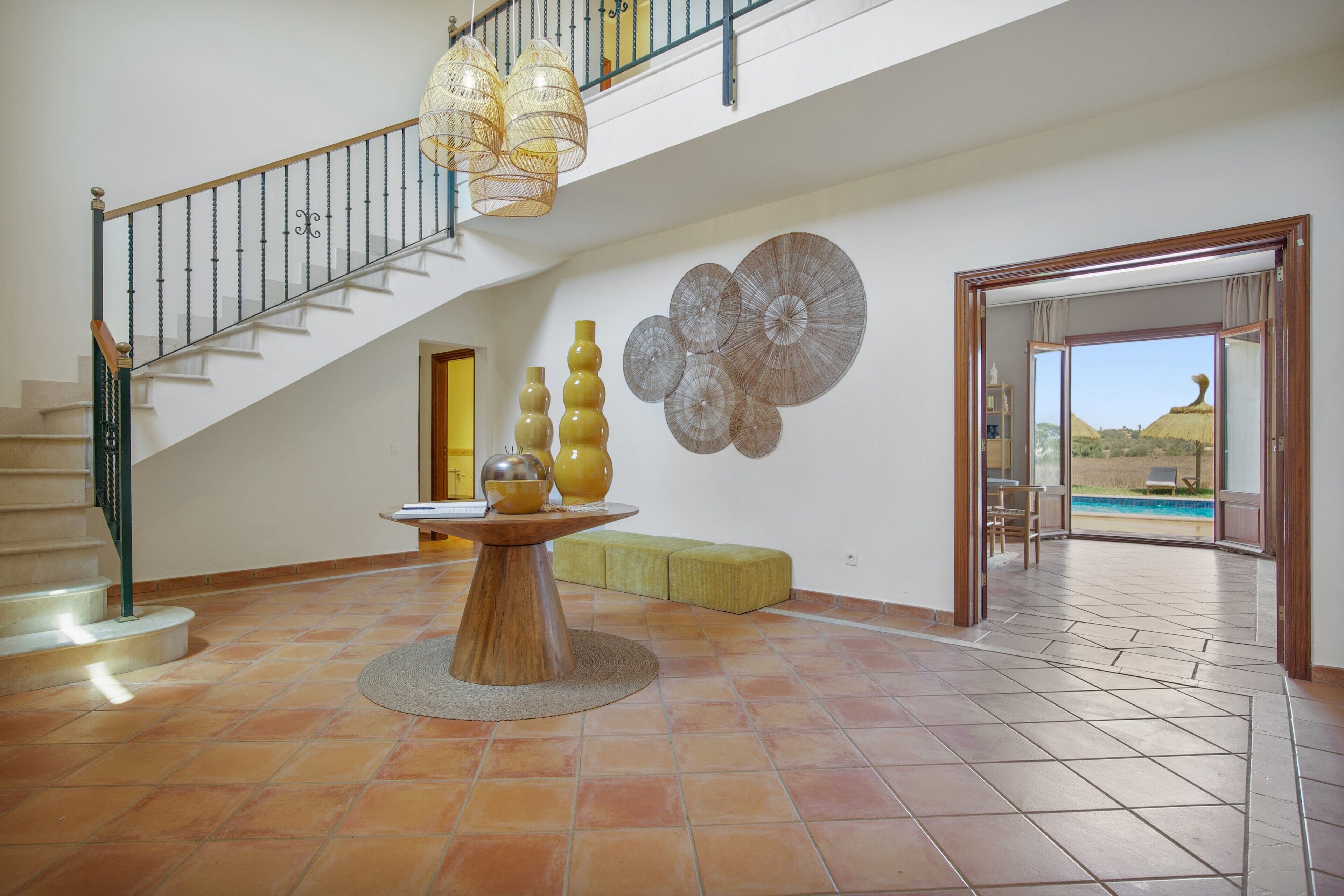 Un intérieur spacieux avec un escalier, un coin repas doté d’une table ronde et une vue sur une piscine extérieure.