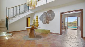Un intérieur spacieux avec un escalier, un coin repas doté d’une table ronde et une vue sur une piscine extérieure.