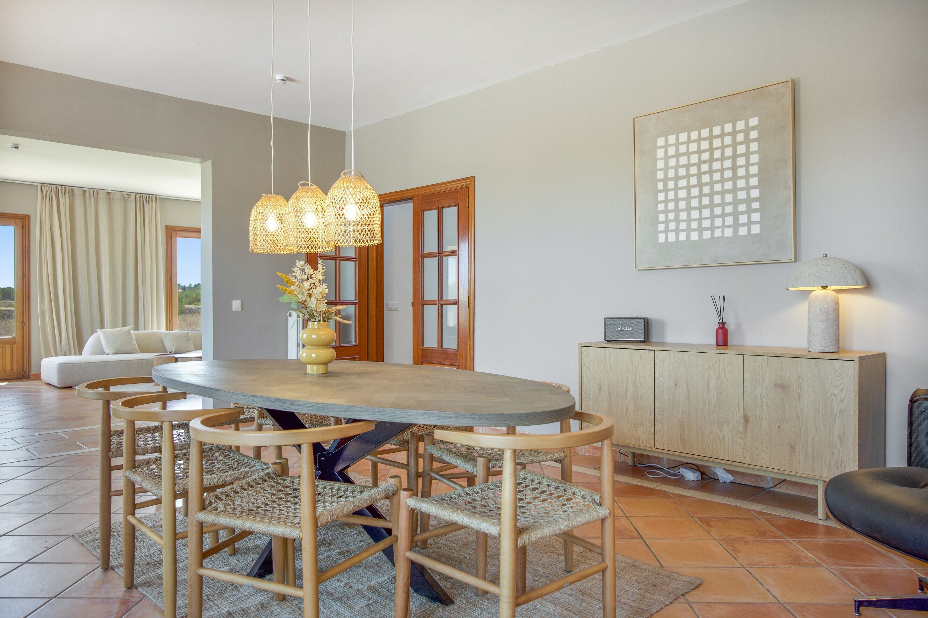 Un espace repas avec une table ronde, des chaises en osier et un luminaire suspendu.