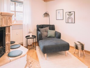 A cozy living room with a sofa, a small side table, a lamp, and a fireplace.