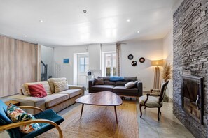 Una sala de estar con un sofá, una mesa de centro, una silla y una chimenea.