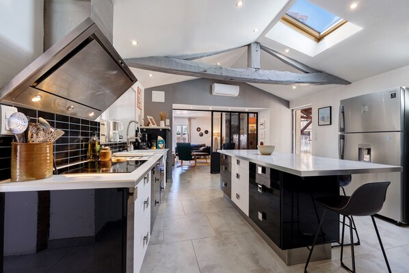 A modern kitchen with a central island, a built-in oven, and a skylight.