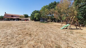 Una propiedad residencial con una casa, patio cercado y área de juegos.