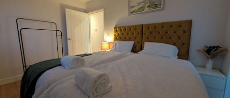 A hotel room with a large bed, a nightstand, a lamp, and a painting on the wall.