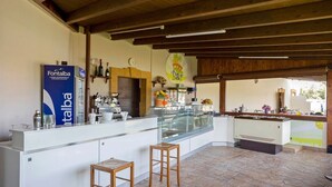 Un espace bar comprenant un comptoir, des tabourets et un distributeur d’eau Fontabella.