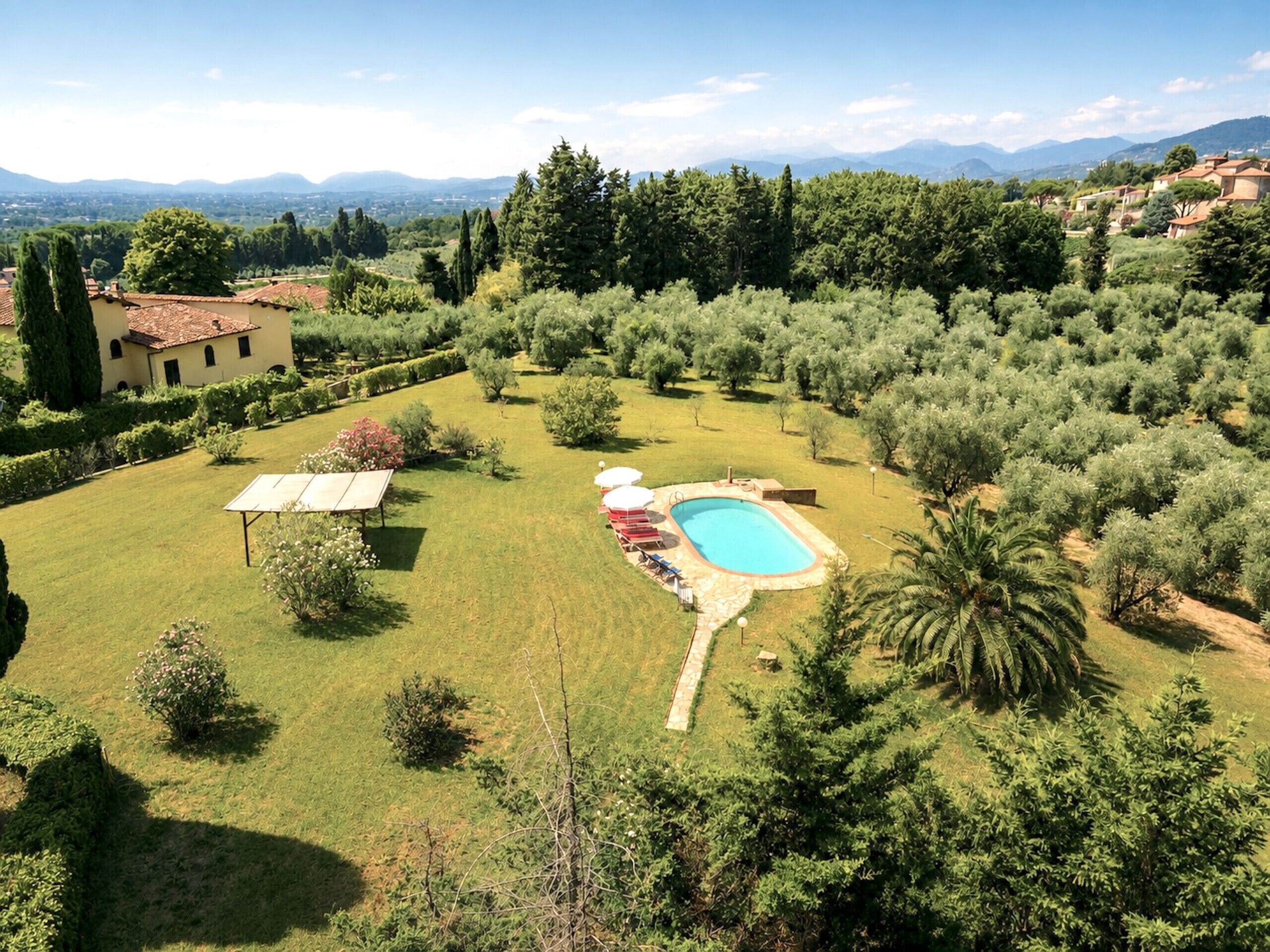 Une propriété résidentielle dotée d’une piscine, d’une végétation luxuriante et offrant une vue sur les montagnes lointaines.
