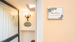 A hallway with a 'Welcome' sign, a framed welcome sign, and a trash can. - Gaetano Spadaro Estate, Pendolino Apartment (Capannori)